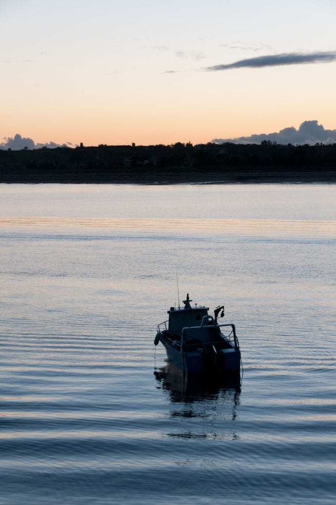 A little fishing boat at sunset off Gorey Pier, St. Martin, Jersey, Channel Islands