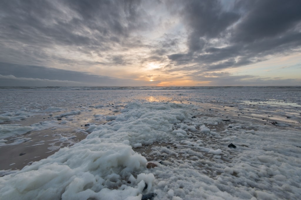 Beachscape showing loads of foam flying off the waves on a really windy day at sunset, taken at Les Laveurs Slip, St. Ouen's Bay, St. Ouen, Jersey, Channel Islands