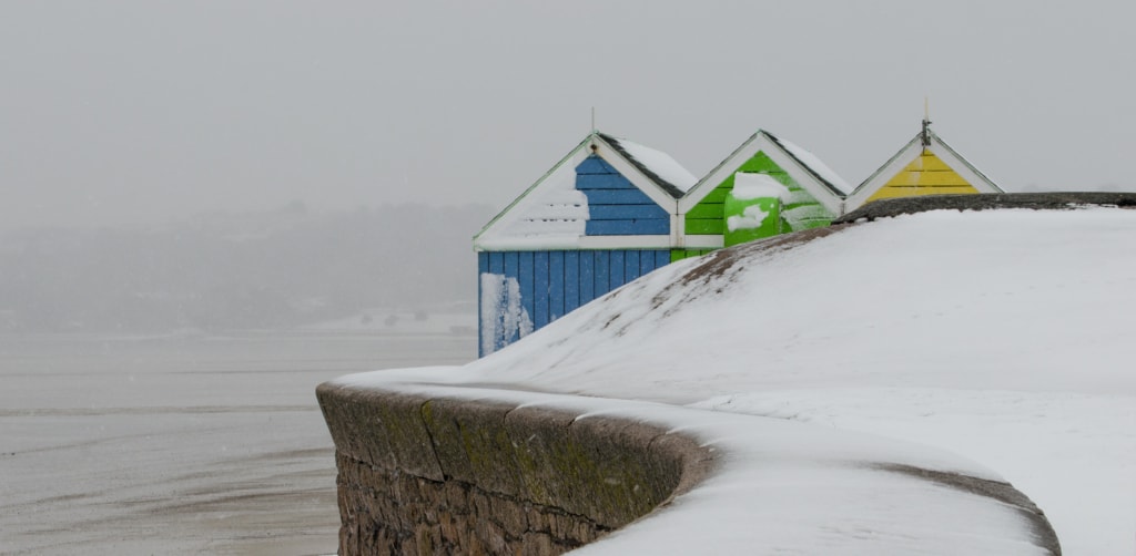 Blue, green and yellow hut in the snow, on the slipway at Bel Royal, St. Lawrence, Jersey, Channel Islands