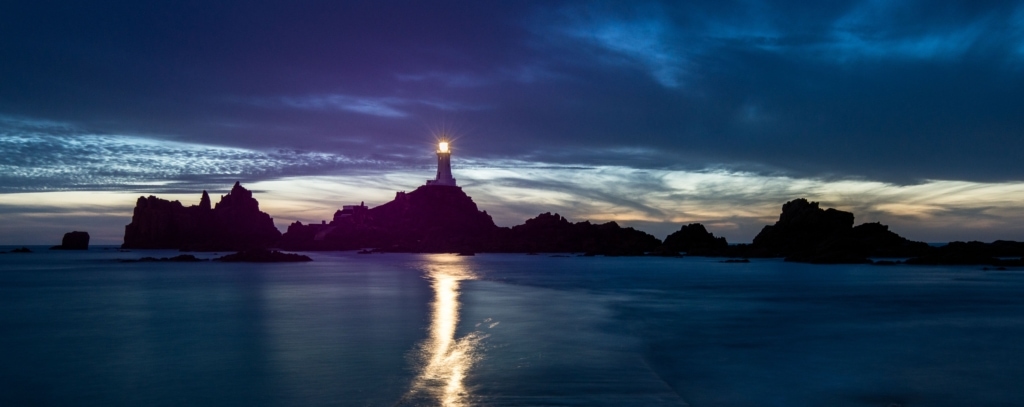 Corbiere Lighthouse after dark as the tide recedes over the causeway, St. Brelade, Jersey, Channel Islands