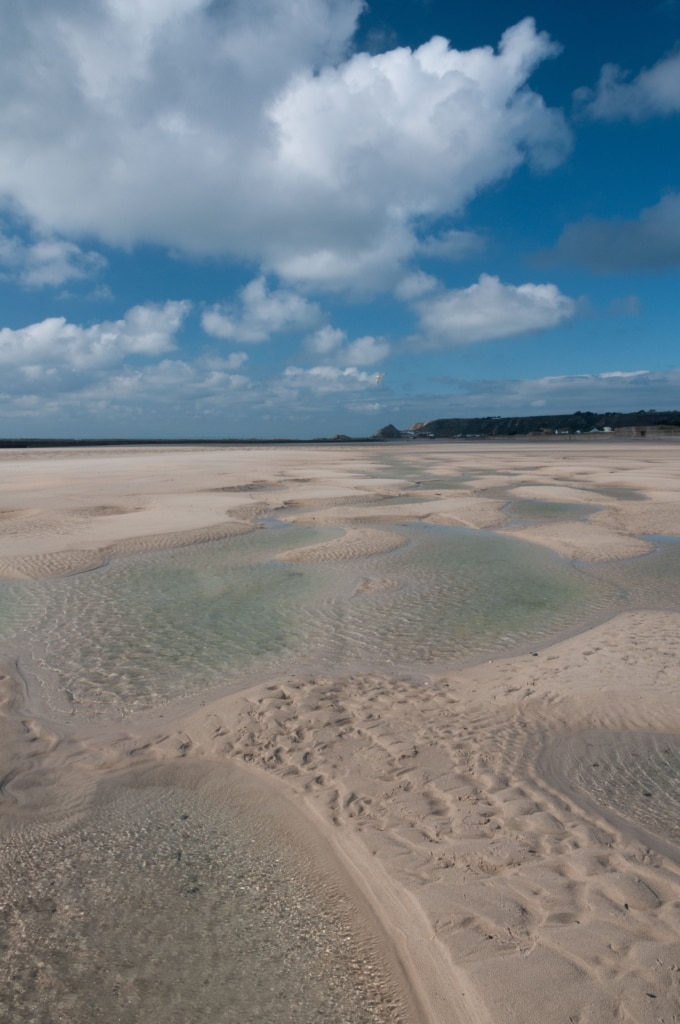 Fluffy clouds and sand patterns and puddles on the beach at St. Ouen's Bay, St. Ouen, Jersey, Channel Islands