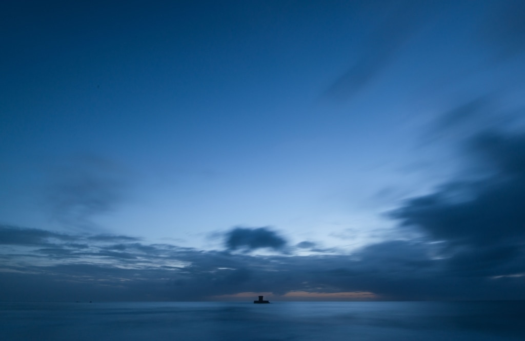 Long exposure seascape showing the clouds and tide and La Rocco Tower after sunset, taken from Le Braye Slipway, St. Brelade, Jersey, Channel Islands