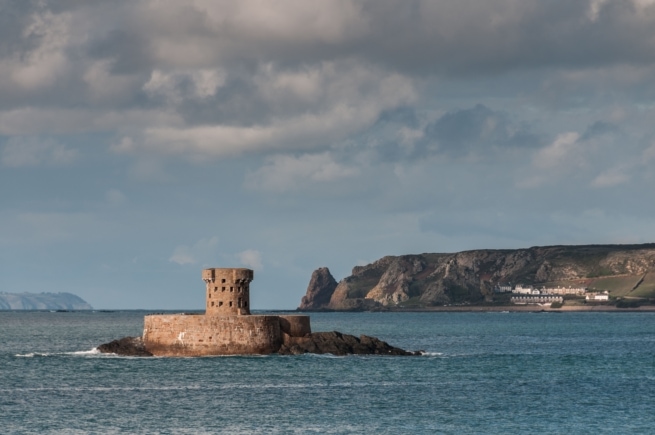 La Rocco Tower and Le Pinacle and Guernsey in the sunlight from La Pulente, St. Brelade, Jersey, Channel Islands