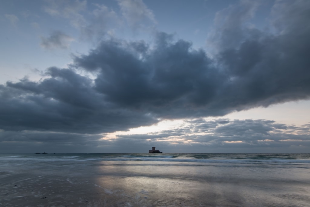 La Rocco Tower at sunset with big fluffy clouds and colours reflecting on the gentle waves, taken between El Tico and Le Braye, St. Peter, Jersey, Channel Islands