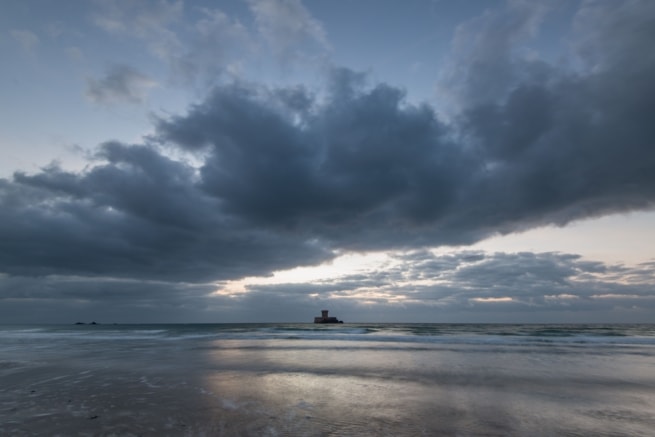 La Rocco Tower at sunset with big fluffy clouds and colours reflecting on the gentle waves, taken between El Tico and Le Braye, St. Peter, Jersey, Channel Islands