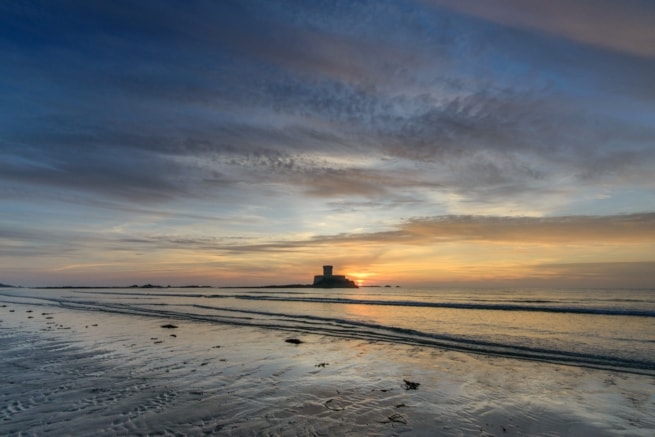 La Rocco Tower at sunset with the clouds and colours reflecting on the gentle waves, taken between El Tico and Le Braye, St. Peter, Jersey, Channel Islands