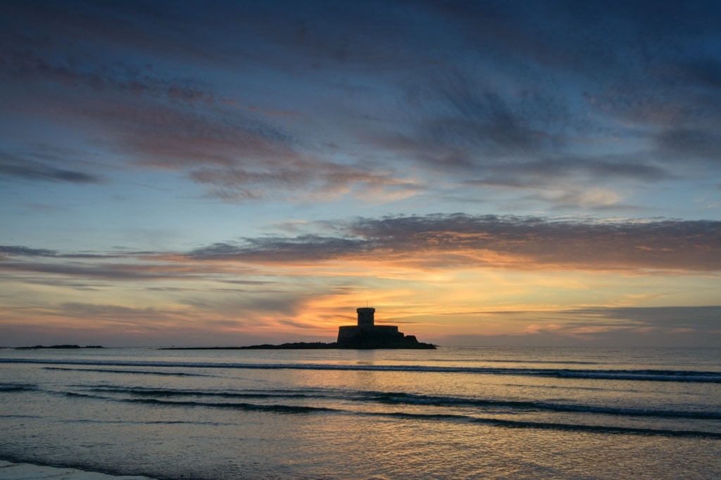 La Rocco Tower at sunset with the clouds and colours reflecting on the gentle waves, taken between El Tico and Le Braye, St. Peter, Jersey, Channel Islands