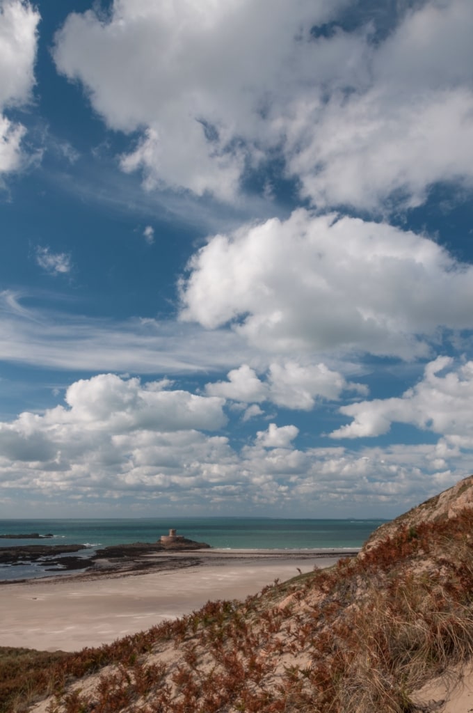 La Rocco Tower and St. Ouen's Bay and fluffy clouds from the headland at La Carriere, St. Brelade, Jersey, Channel Islands