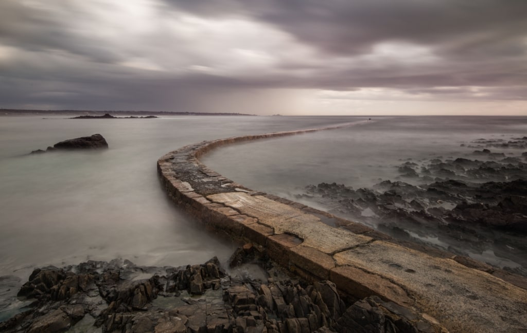 Long exposure of the little jetty at L'Etacq on a grey day, as the tide rises over it, St. Ouen, Jersey, Channel Islands