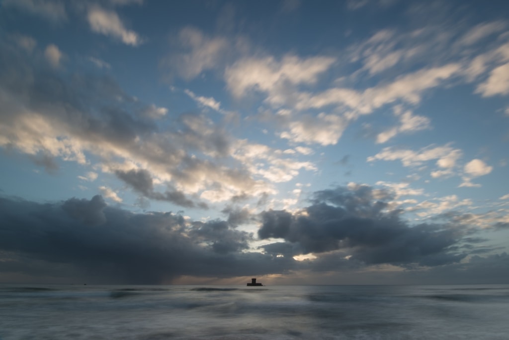 Long exposure seascape showing the clouds and tide and La Rocco Tower at sunset, taken from Le Braye Slipway, St. Brelade, Jersey, Channel Islands