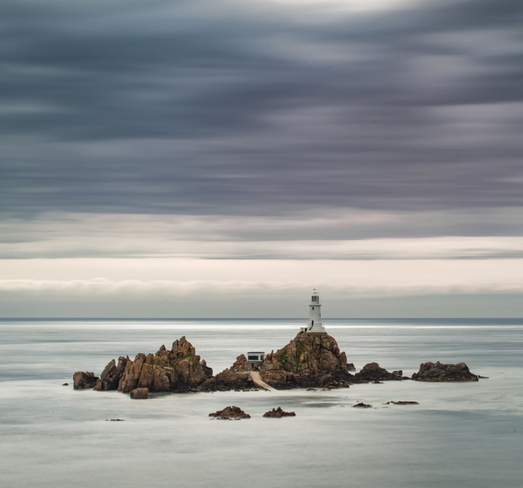 Long exposure seascape showing Corbiere Lighthouse on a grey and cloudy day, St. Brelade, Jersey, Channel Islands