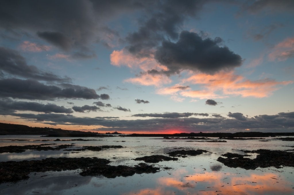 Low tide sunset on the beach at Le Braye looking towards Corbiere Lighthouse, St. Brelade, Jersey, Channel Islands