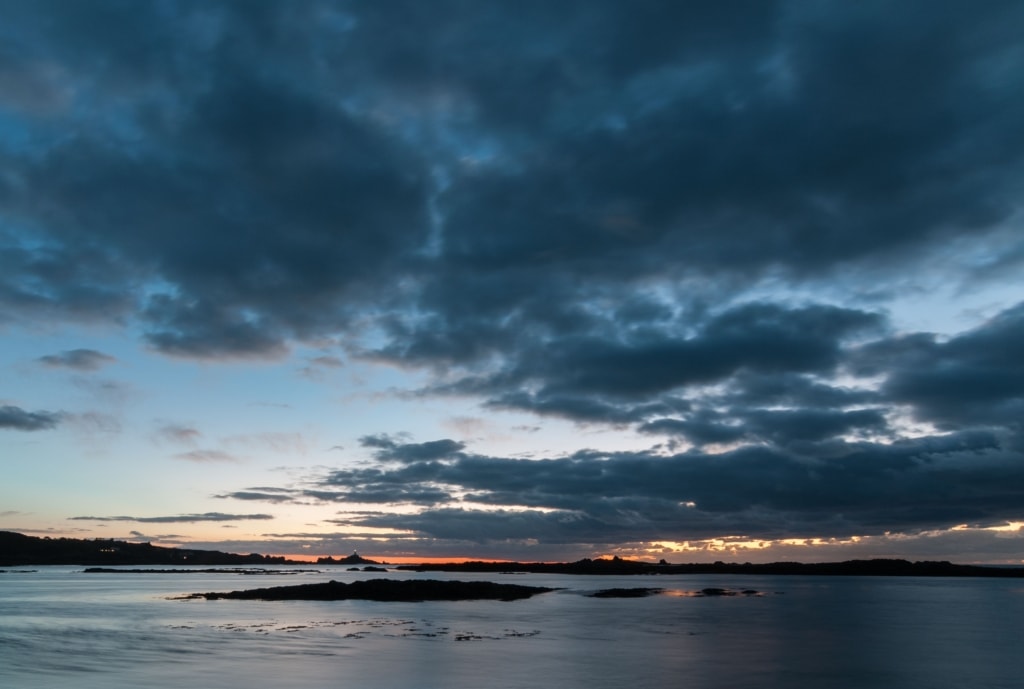 Low tide sunset on the beach at Le Braye looking towards Corbiere Lighthouse, St. Brelade, Jersey, Channel Islands