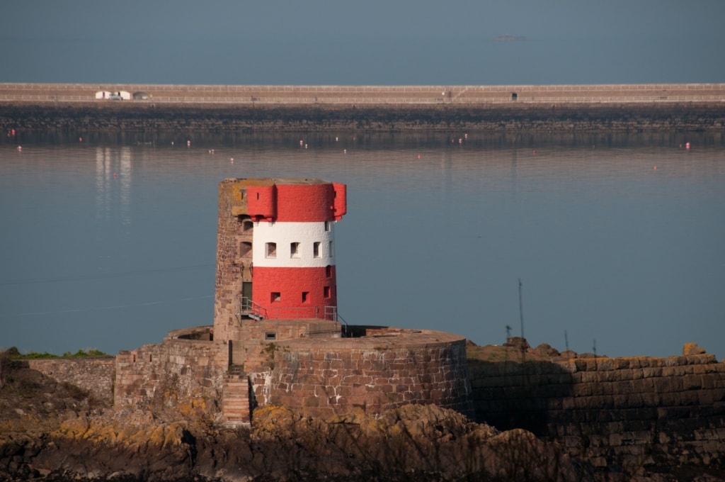 Red and white Martello Tower at Archirondel, St. Martin, with St. Catherine's Breakwater behind, Jersey, Channel Islands