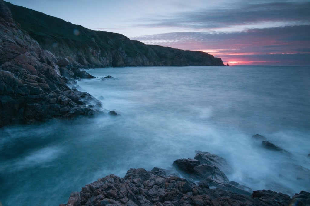 Sunset across Plemont Bay looking along the North Coast towards La Cotte a la Chevre, St. Ouen, Jersey, Channel Islands