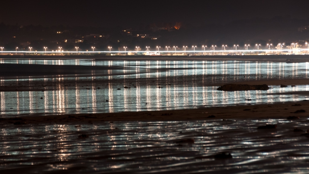 Promenade lighting reflected in the wet sand at St. Aubin's Bay, West Park, St. Helier, Jersey, Channel Islands