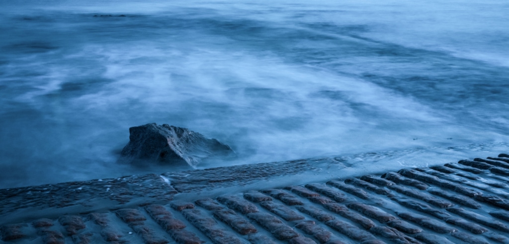 Long exposure of the sea swirling around a rock at Green Island Slipway, St. Clement, Jersey, Channel Islands