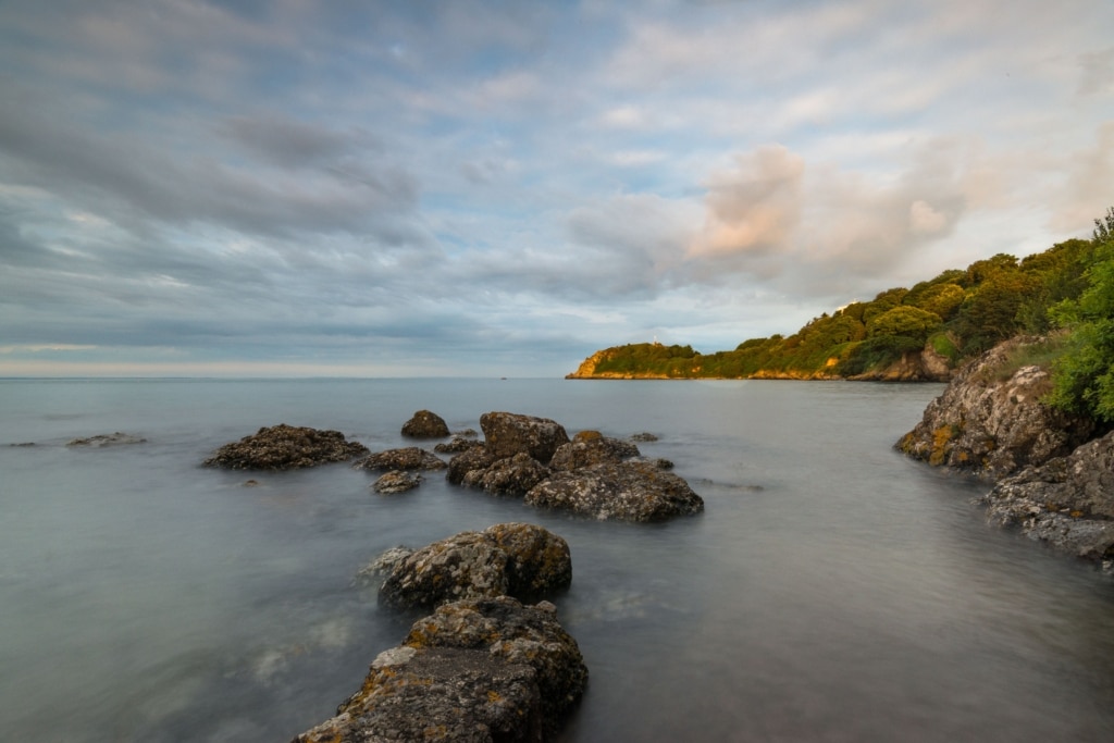 Seascape featuring rocks and clouds at high tide in the evening light at La Saie Harbour, Jersey, Channel Islands