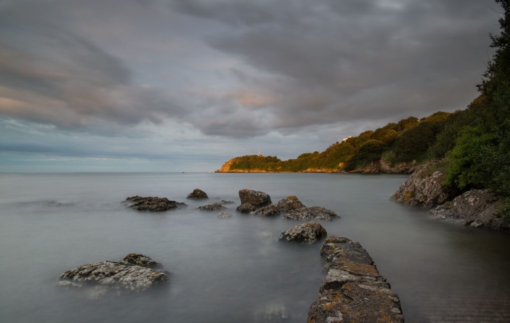 Seascape featuring rocks and clouds at high tide in the evening light at La Saie Harbour, Jersey, Channel Islands