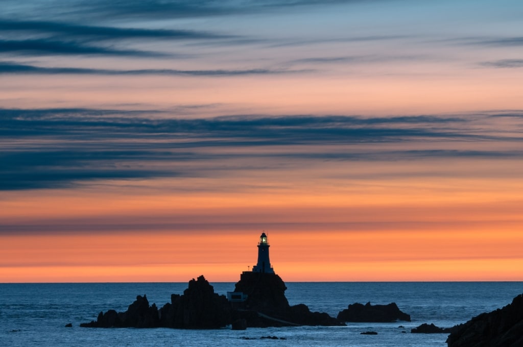 Silhouette of Corbiere Lighthouse with vibrant clouds at sunset, from La Rosiere, St. Brelade, Jersey, Channel Islands