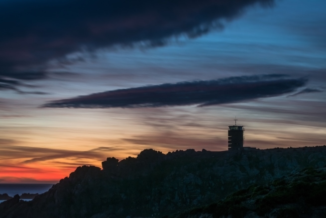 Silhouetted cliffs and the Radio Tower with vibrant clouds after sunset from La Rosiere, St. Brelade, Jersey, Channel Islands