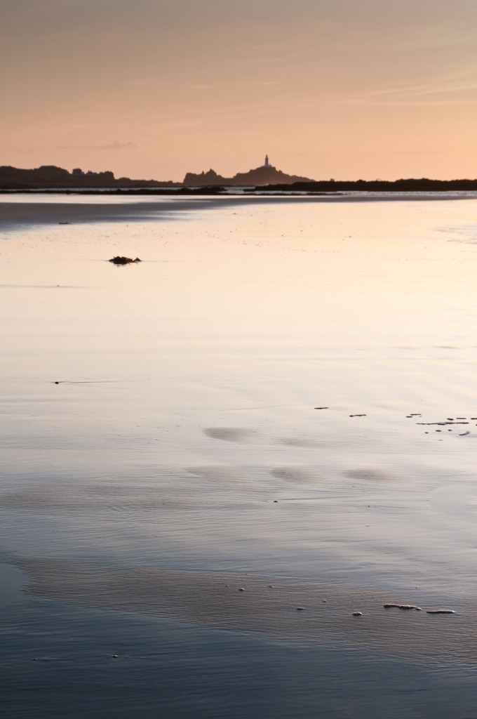 Silver reflection on the wet sand on the beach at sunset, looking towards Corbiere Lighthouse, from in between Le Braye and El Tico, St. Ouen's Bay, St. Ouen, Jersey, Channel Islands