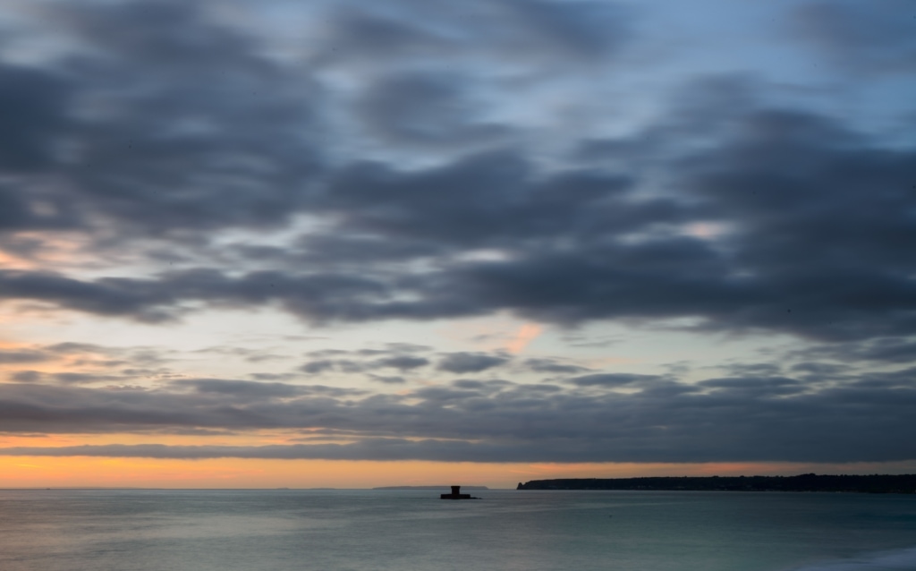 Seascape looking across St. Ouen's Bay towards La Rocco Tower and Le Pinacle and the other islands at sunset, taken from La Pulente, St. Brelade, Jersey, Channel Islands