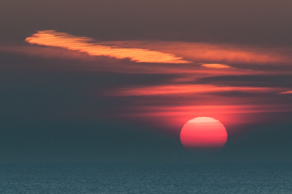 Strange cloud patterns and a giant pink sun as the sun sets over the sea, taken at La Mare Slip, St. Clement, Jersey, Channel Islands