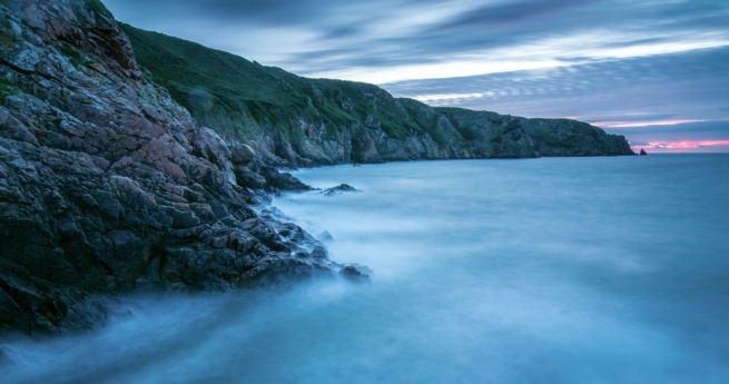 Sunset across Plemont Bay looking along the North Coast towards La Cotte a la Chevre, St. Ouen, Jersey, Channel Islands