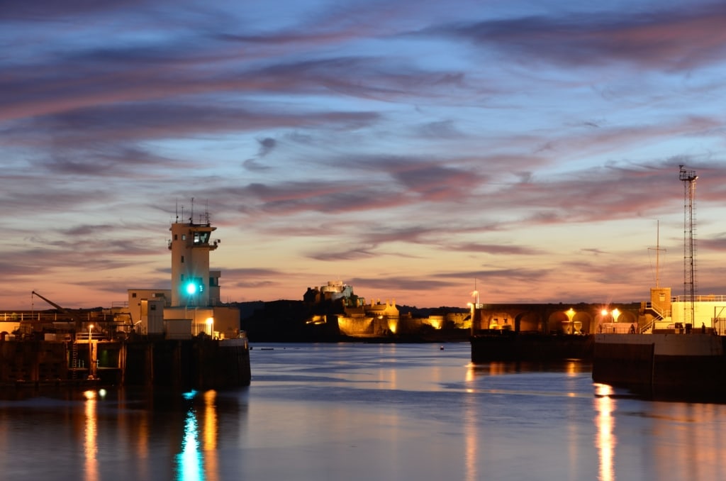 Beautiful sunset looking across St. Helier Harbour towards the Port Control Tower and Elizabeth Castle, and just after dark when the harbour lights come on, St. Helier, Jersey, Channel Islands