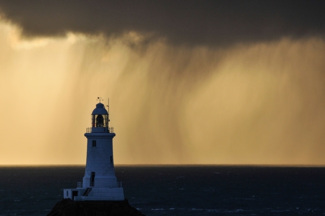 Seascape showing sunset at Corbiere Lighthouse during a really heavy rain storm, Corbiere, St. Brelade, Jersey, Channel Islands