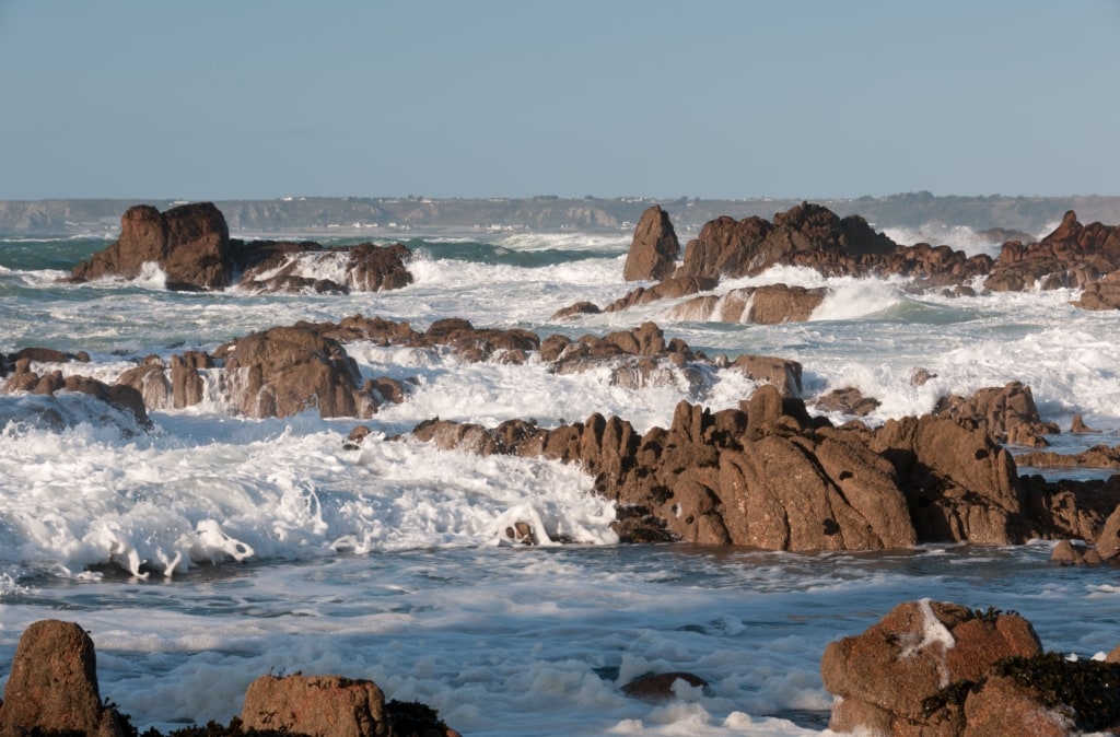 Surf and rocks looking across St. Ouen’s Bay from Corbiere Lighthouse Causeway, St. Brelade, Jersey, Channel Islands