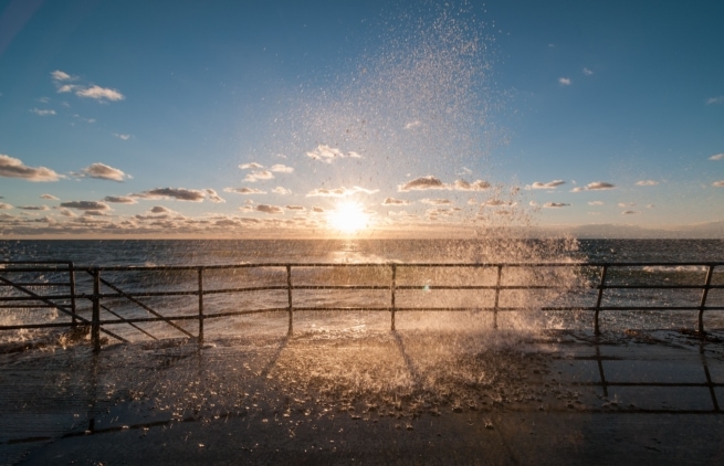 Waves bouncing off the sea wall at sunset, St. Ouen's Bay, St. Peter, Jersey, Channel Islands